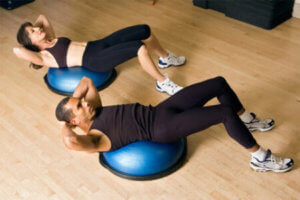 a man and women laying on bosu domes on the floor