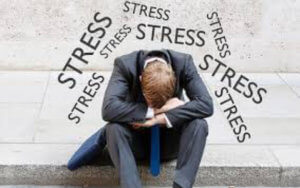 a business man bent over with head in knees and the word stress around their head