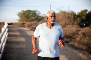 older man running with hand weights