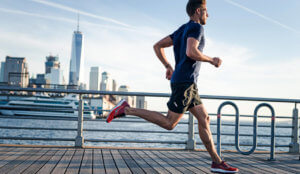 man running along a wooden board walk with a city background