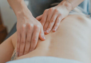 female hands massaging a clients back while they are laying down