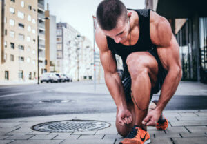 male runner kneeling tieing up their shoe lace