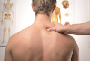 therapist squeezing the shoulder muscles of a patient sitting down