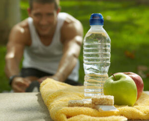 man stretching with a towel water bottle and apple in front of them