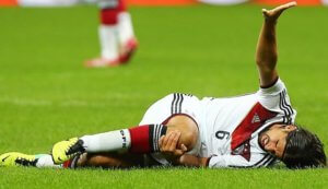 image: male soccer player on the ground holding knee in pain