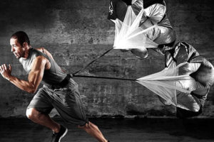 image: man running with an exercise parachute attached to their waist