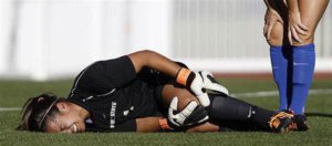 image: female soccer player laying on ground holding left knee