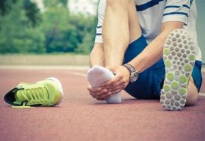 image:runner wtting on the ground with one shoe off holding their foot