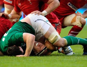 image:rugby union player falling on their neck and shoulder in a pack of players