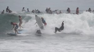 image: lots of people surfing a wave